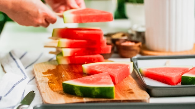 Paso a paso. Deslizar el palito de paleta de madera en la cuña de sandía para hacer paletas heladas de sandía.