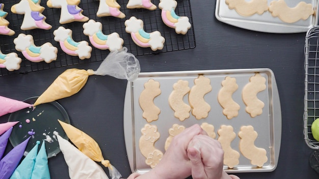 Paso a paso. Endecha plana. Decoración de galletas de azúcar de unicornio con glaseado real en una bandeja para hornear.