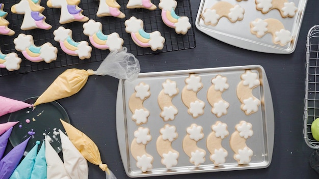 Paso a paso. Endecha plana. Decoración de galletas de azúcar de unicornio con glaseado real en una bandeja para hornear.