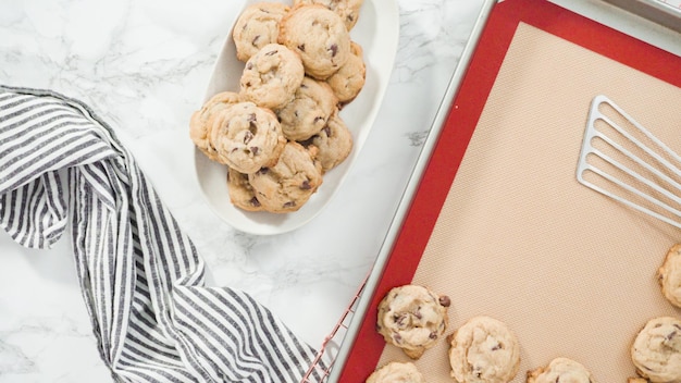 Paso a paso. Endecha plana. Galletas de chispas de chocolate suaves caseras recién horneadas en una bandeja para hornear.