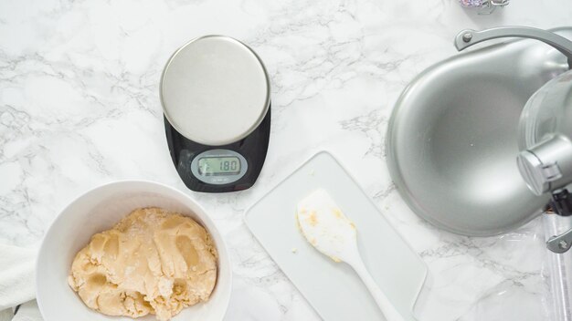 Paso a paso. Endecha plana. Medición de la masa de galletas con una báscula de cocina digital para hornear galletas de azúcar de molinillo rojas, blancas y azules.