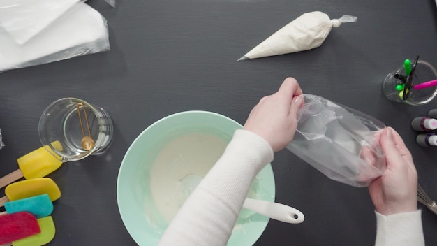 Paso a paso. Endecha plana. Verter glaseado real en la manga pastelera para decorar las galletas de azúcar.