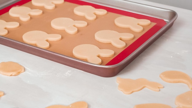 Paso a paso. Galletas de azúcar de Pascua sin hornear dispuestas para hornear en una bandeja para hornear.