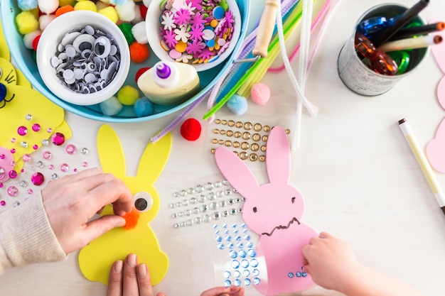 Paso a paso. Madre e hija decorando conejitos de Pascua.