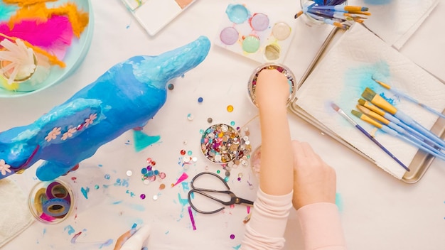 Paso a paso. Madre e hija decorando unicornio de papel maché juntas.