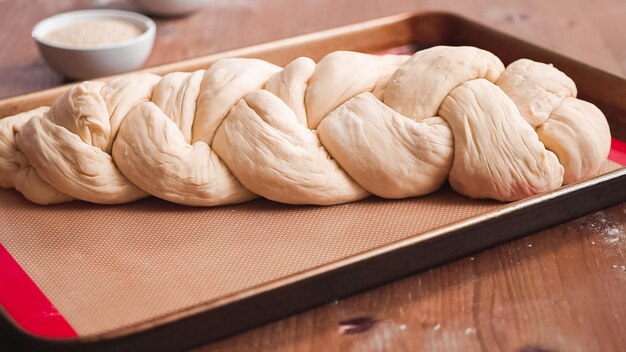 Paso a paso. Masa de jalá brazada en hogaza de pan en una bandeja para hornear.