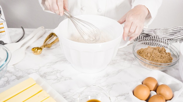 Paso a paso. Mezclar ingredientes en un recipiente de vidrio para hacer galletas con trocitos de chocolate.