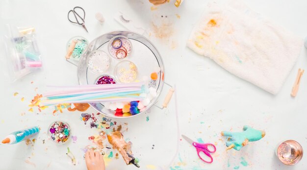 Foto paso a paso. niñas decorando unicornios de papel maché con purpurina y flores de papel.