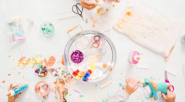 Paso a paso. Niñas decorando unicornios de papel maché con purpurina y flores de papel.