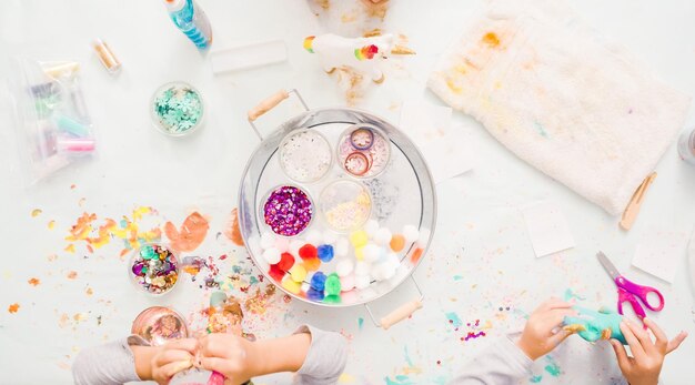 Paso a paso. Niñas decorando unicornios de papel maché con purpurina y flores de papel.