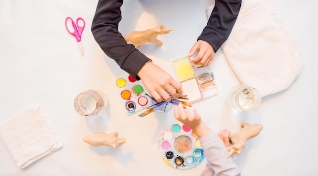 Paso a paso. Niñas pintando unicornios de papel maché con pintura acrílica.