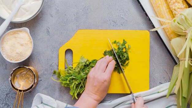 Paso a paso. Picar cilantro en una tabla para cortar madera.