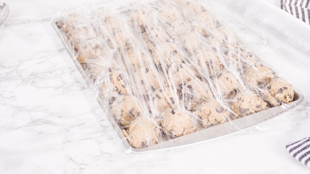 Paso a paso. Sacar galletas de chispas de chocolate caseras con una cuchara de masa de metal en la bandeja para hornear.