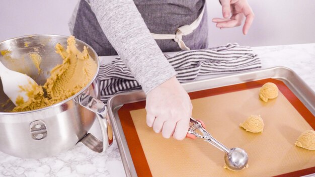 Paso a paso. Sacar la masa de galletas de mantequilla de maní con una cuchara para masa en la bandeja para hornear.