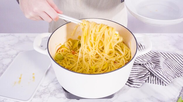 Paso a paso. Sirviendo una pasta de una olla en un plato de pasta blanca.