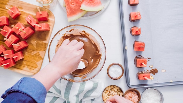 Paso a paso. Sumergir cubos de sandía en chocolate derretido y decorar con sal marina y almendras.