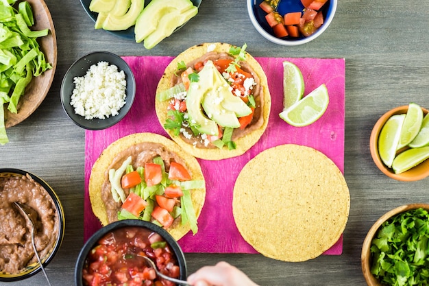 Paso a paso. Tostadas mexicanas vegetarianas frescas sobre tabla de cortar morada.