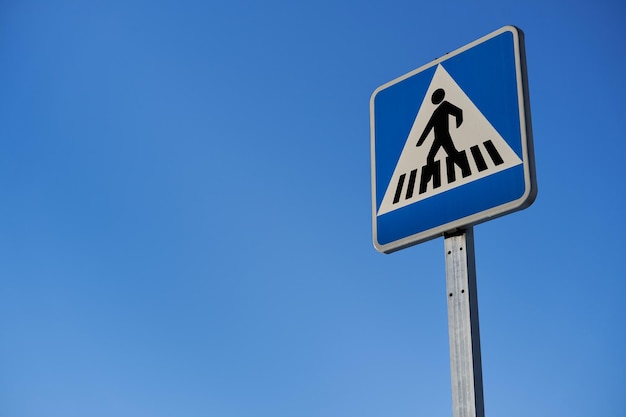 Paso de peatones de la señal de tráfico sobre el cielo azul