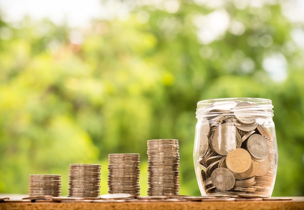 Paso de pilas de monedas y dinero en el frasco con fondo de naturaleza