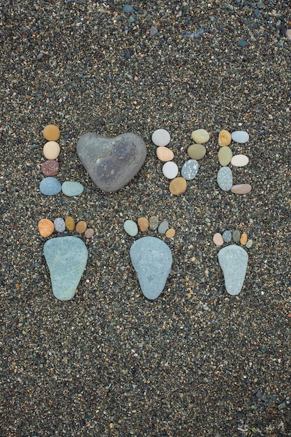 Pasos de hombre, mujer y niño hechos de piedras en la playa de arena