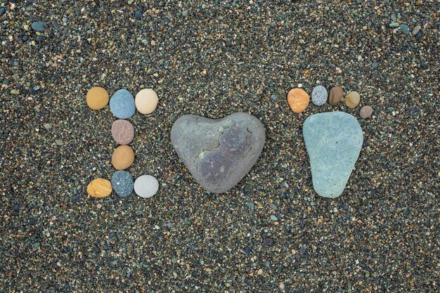 Pasos de hombre, mujer y niño hechos de piedras en la playa de arena