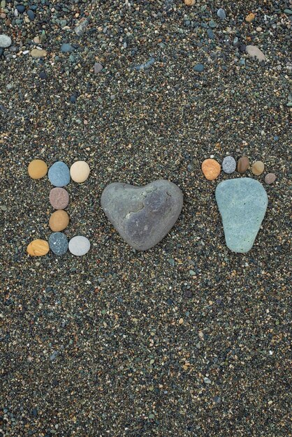 Pasos de hombre, mujer y niño hechos de piedras en la playa de arena