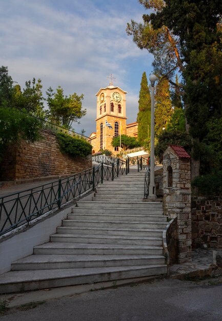 Pasos a la iglesia ortodoxa santa de los santos Anargyri con un reloj y una cruz en Grecia