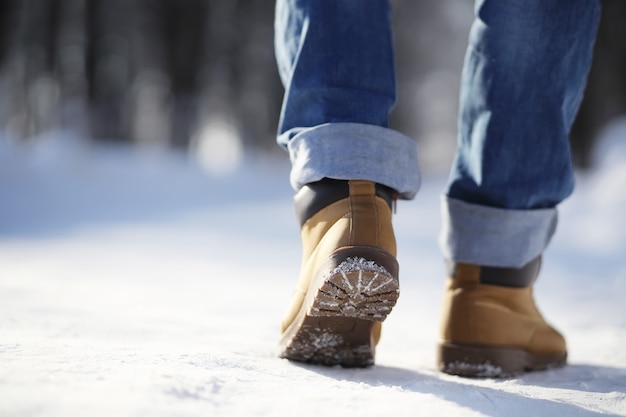 Pasos a lo largo del camino cubierto de nieve. Un hombre camina en el parque en invierno.