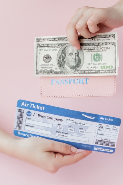 Pass, Dollar und Flugticket in der Frauenhand auf einem rosa Hintergrund. Reisekonzept, Kopie, Raum