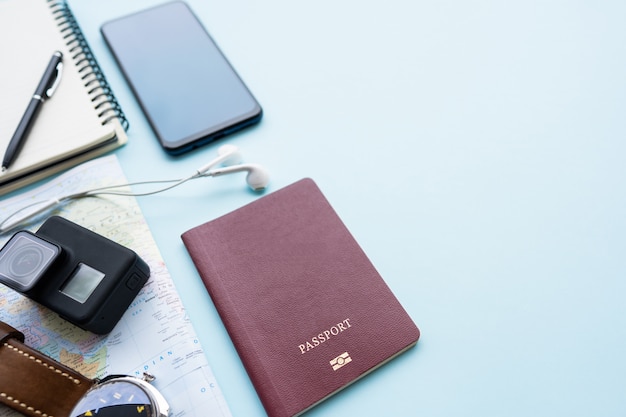 Pass mit einer Karte auf blauem Pastellhintergrund Reiseplanung Draufsicht des Reisendzubehörs mit Kamera, Uhr auf Weltkarte Vorbereitung für Reise.
