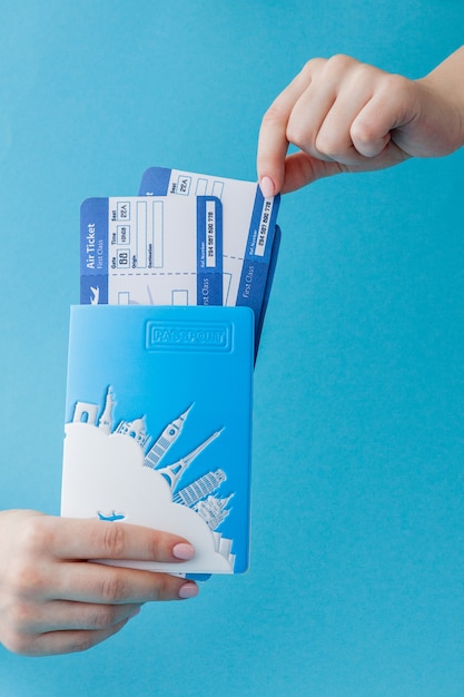 Foto pass und flugticket in der frauenhand auf einem blauen hintergrund. reisekonzept, kopierraum
