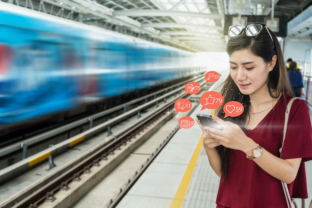 Passageira mulher asiática usando telefone celular para verificar o aplicativo da rede social