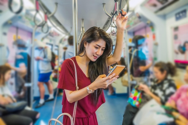 Foto passageiro da mulher asiática com roupa casual usando o telefone móvel inteligente