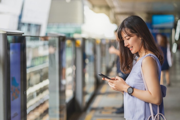 Passageiro de jovem mulher asiática usando rede social via celular inteligente