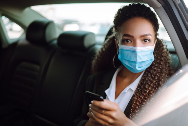 Passageiro de mulher relaxada na máscara médica protetora no carro táxi.