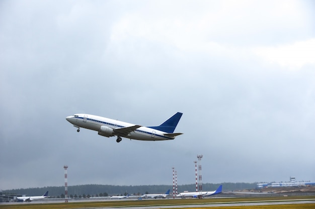 Passageiro decola para o céu da pista do aeroporto em tempo nublado com chuva