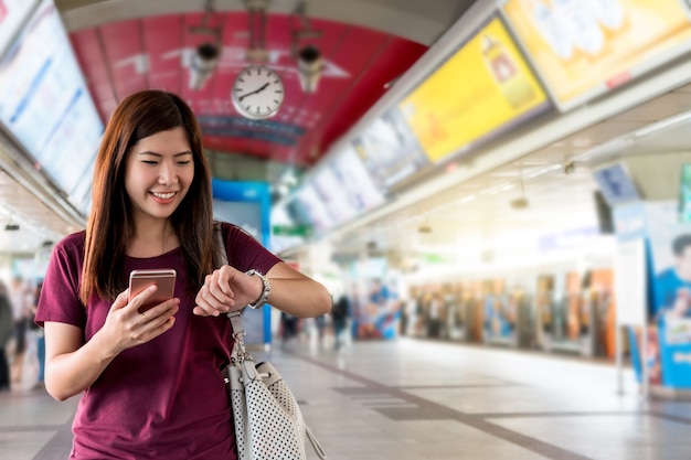 Foto passageiro mulher asiática assistindo o relógio na interexchange entre estação de trilhos skytrain