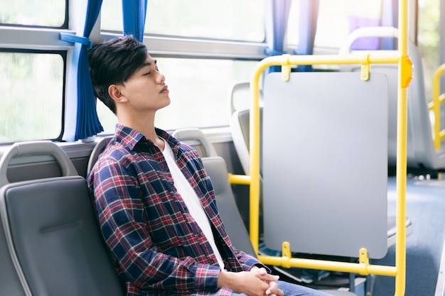 Passageiro sentado e dormindo dentro de um ônibus público durante a viagem.