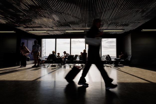 Passageiros com bagagem caminhando ao longo de uma sala de embarque do aeroporto
