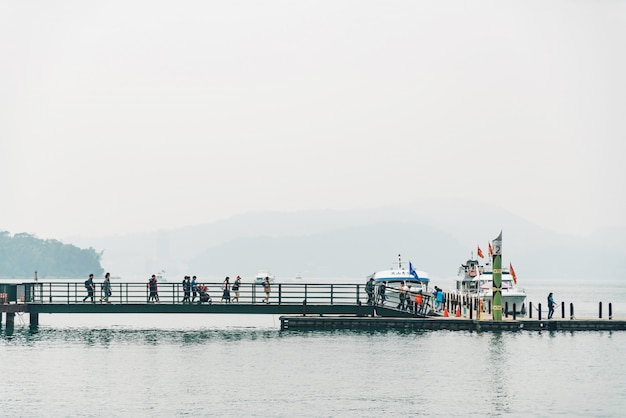 Passagem de madeira a ligação ao barco no lago moon de Sun com montanha e nuvem no fundo no cais de Shuishe no distrito de Yuchi, Nantou County, Taiwan.