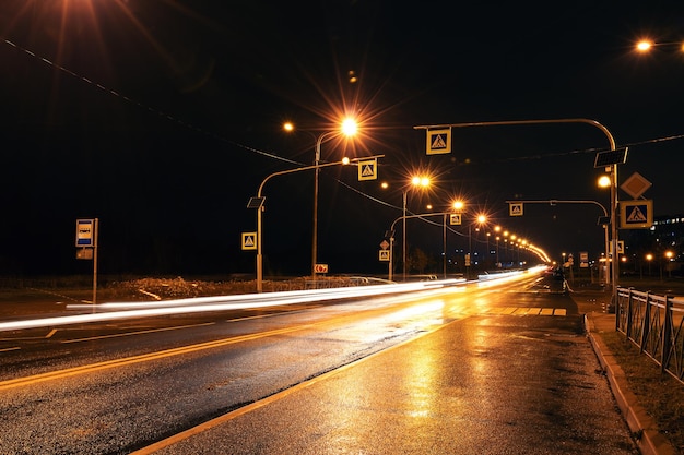 Passagem de pedestres à noite, estrada da cidade luz da rua e asfalto molhado