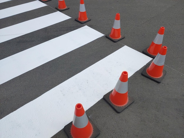 Passagem de pedestres pintada fresca no asfalto marcado com cones de trânsito