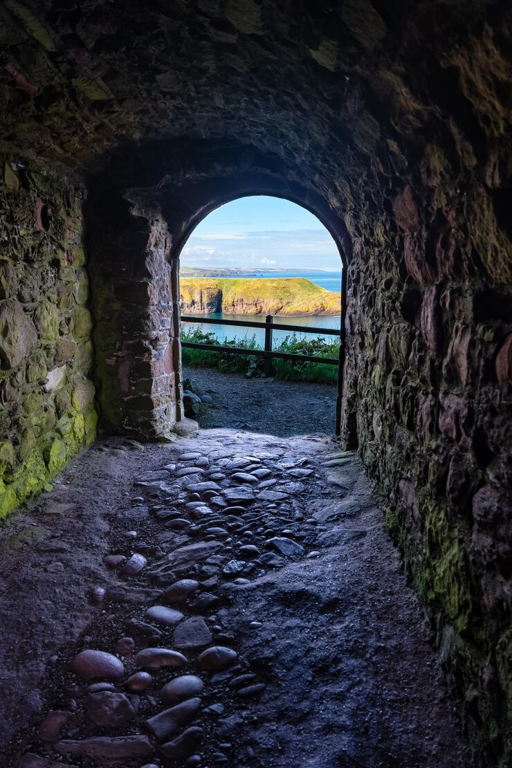 Foto passagem interna que levará a um penhasco com vista para a praia no castelo de dunnottar, escócia