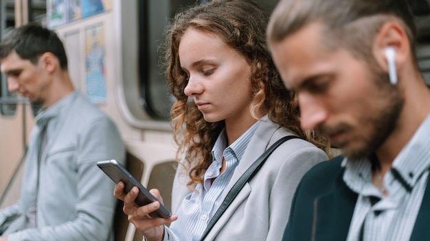 Passagiere, die Smartphones im U-Bahn-Wagen benutzen