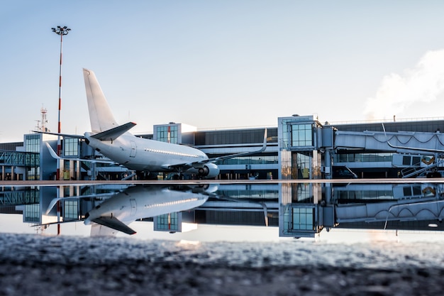 Passagierflugzeug geparkt an einem Jetway mit Spiegelung in einer Pfütze