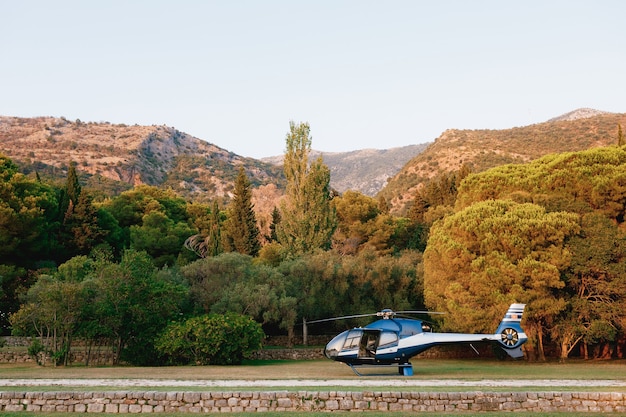 Passagierhubschrauber landete im Park vor der Kulisse der Berge