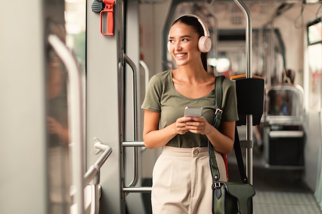 Passagierin steht in der Straßenbahn und hört Musik online am Telefon