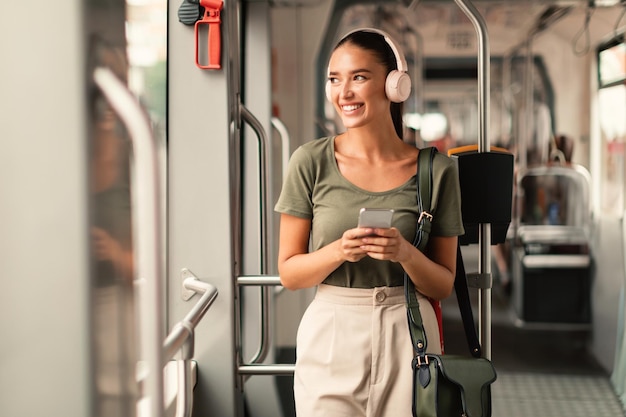 Foto passagierin steht in der straßenbahn und hört musik online am telefon