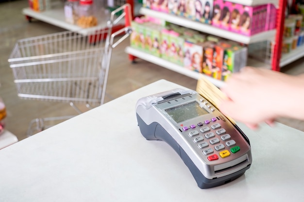 Passando a mão o cartão de crédito no terminal de pagamento do supermercado