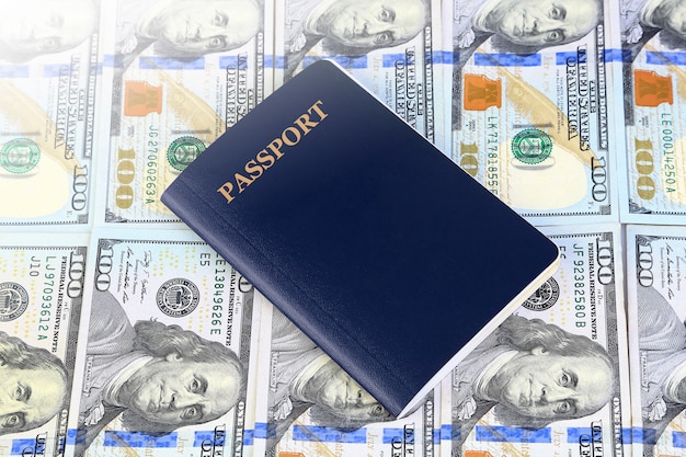 Passaporte azul com muitos cem notas de banco dos dólares, negócio ou conceito de viagem.